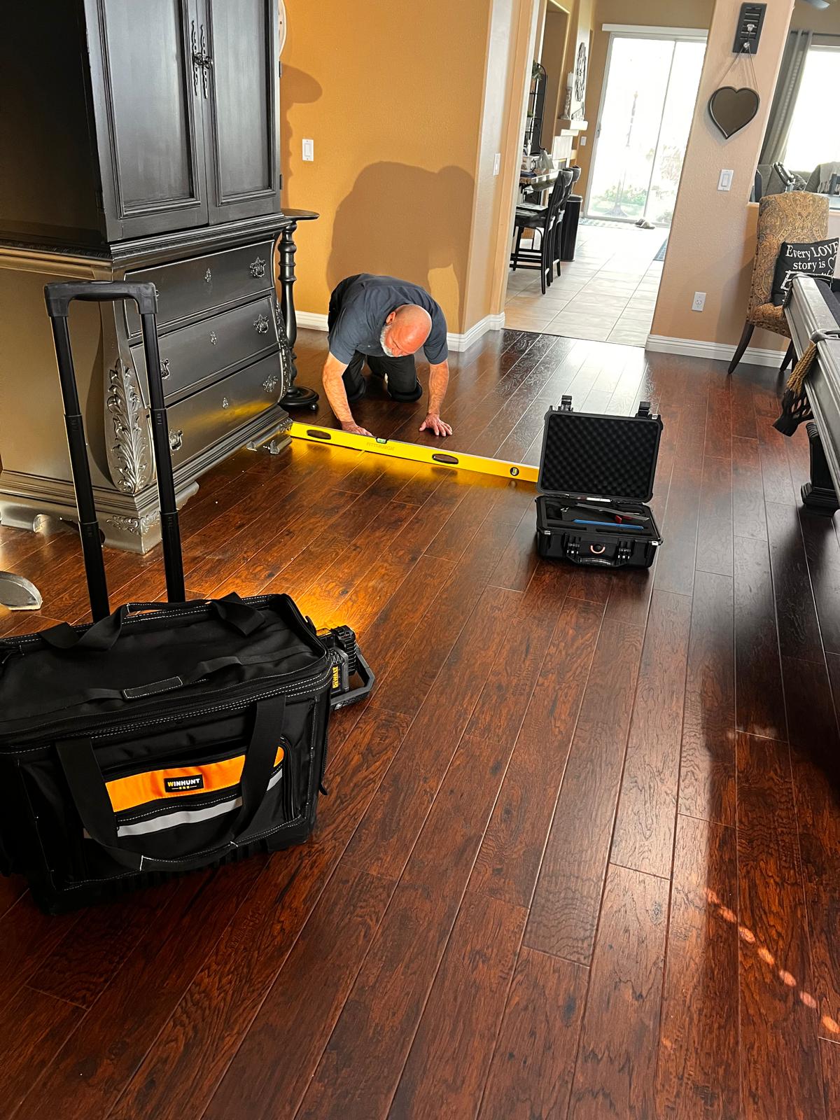 Nick Perez inspecting a hardwood floor with his tools
